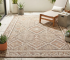 Stylish patterned outdoor rugs enhance a modern patio with plants and a comfortable lounge chair.