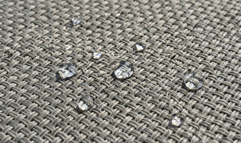 Close-up of water beading on durable, water-resistant outdoor rugs, showcasing quality.