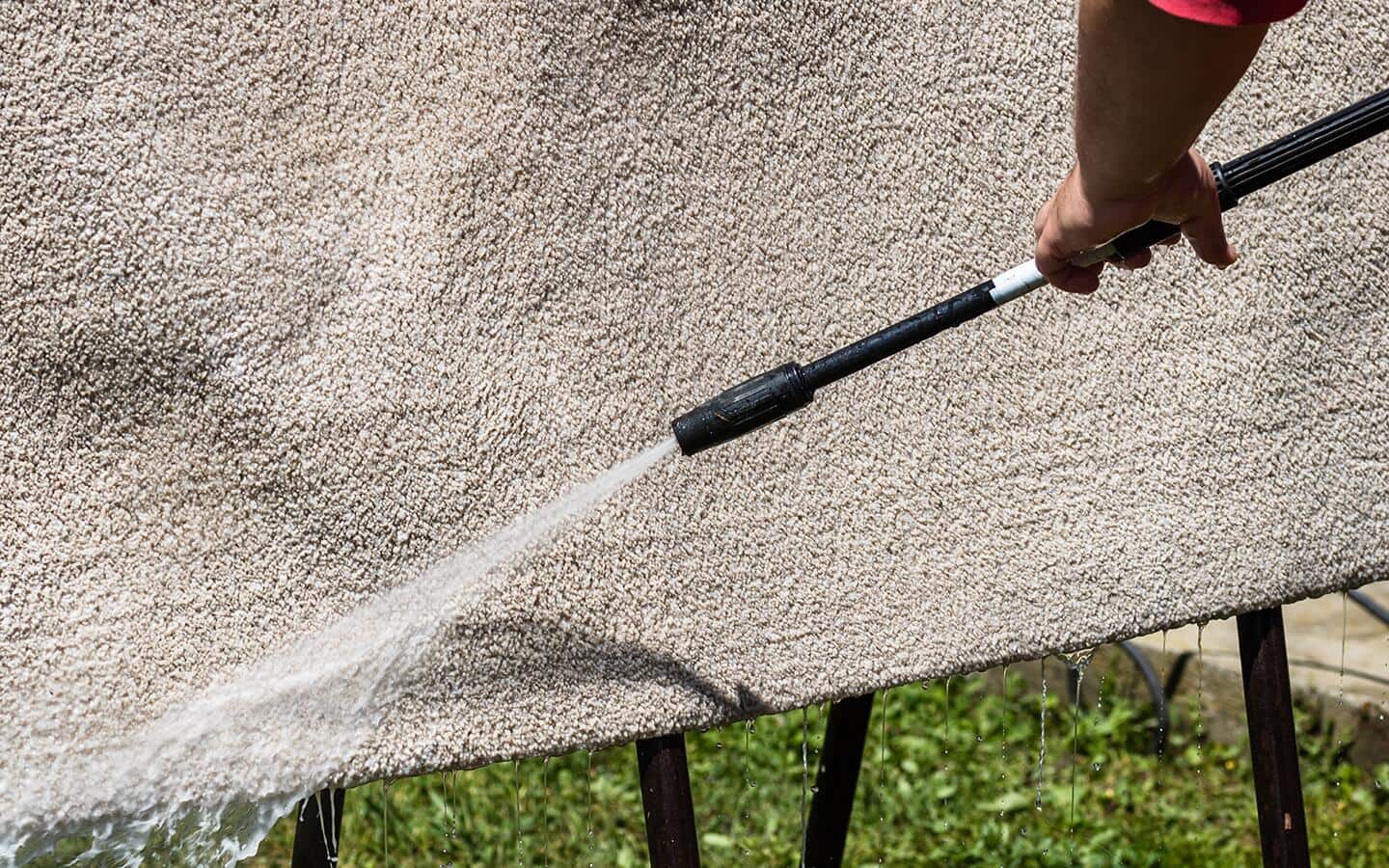 Close-up of pressure washing a durable, cleanable outdoor rugs.