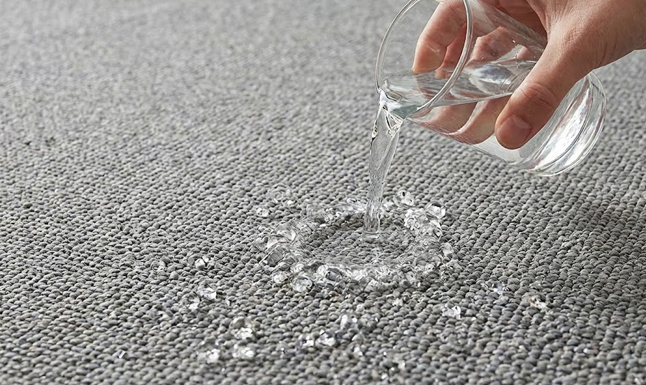 Close-up of water beading on a grey, waterproof outdoor rug, demonstrating durability.